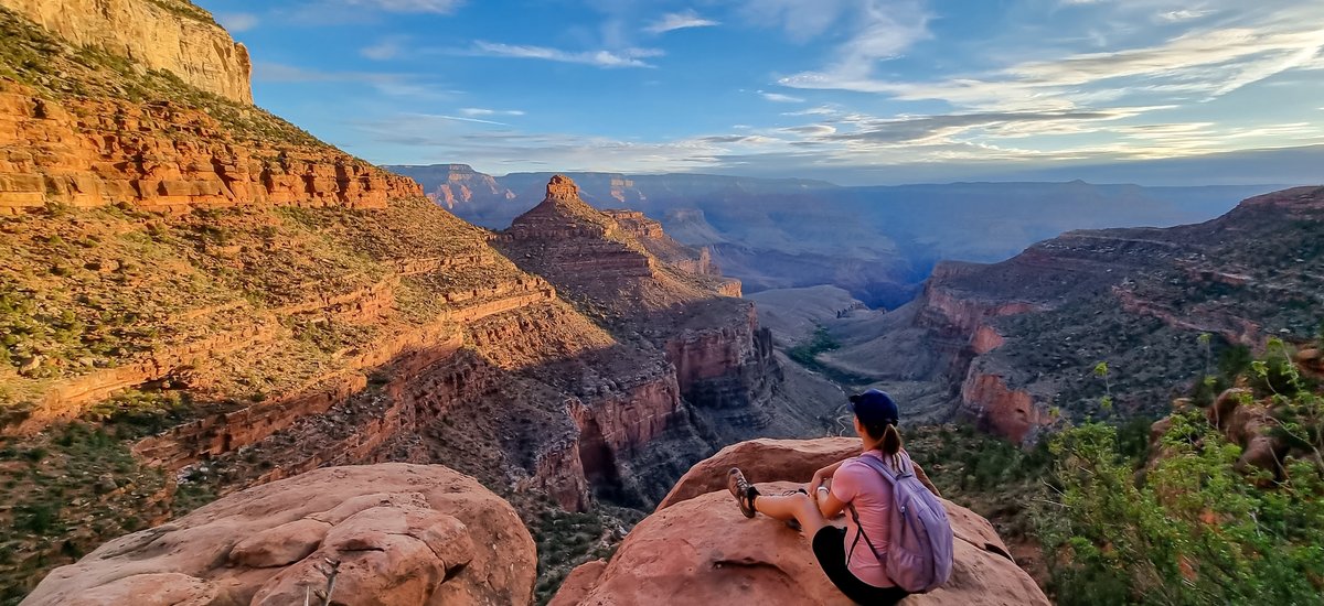 Vue arrière d'une femme avec sac à dos assise sur un rocher le long du sentier Bright Angel avec vue aérienne sur South Rim of Grand Canyon National Park, Arizona, États Unis