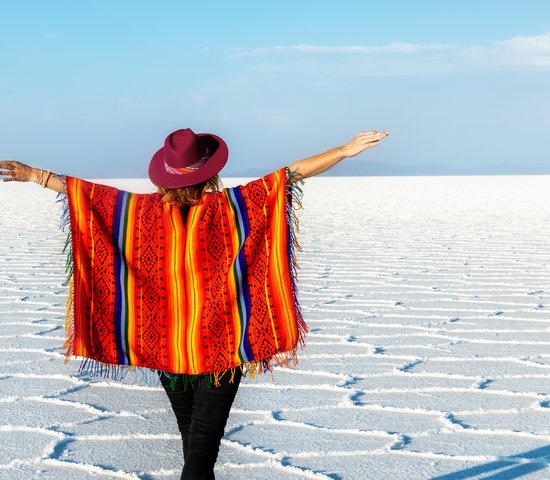 Une fille en chapeau et en poncho devant le Salar d'Uyuni, Bolivie