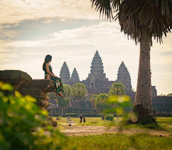 Femme assise sur un rocher devant le temple d'Angkor Wat, Cambodge