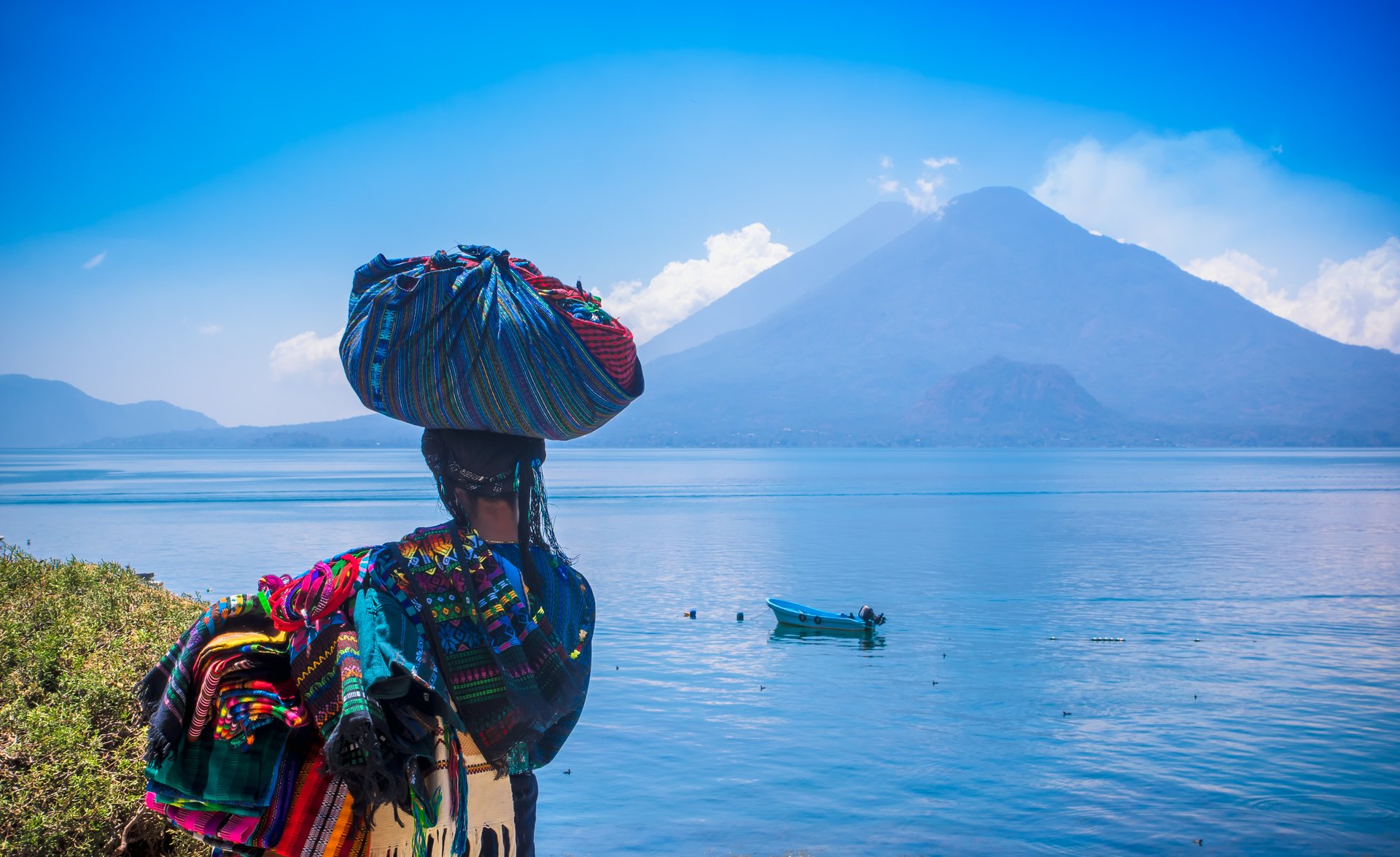 Une femme en tenue traditionnelle de dos devant le lac Atitlan, Guatemala