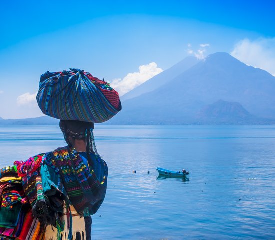 Une femme en tenue traditionnelle de dos devant le lac Atitlan, Guatemala