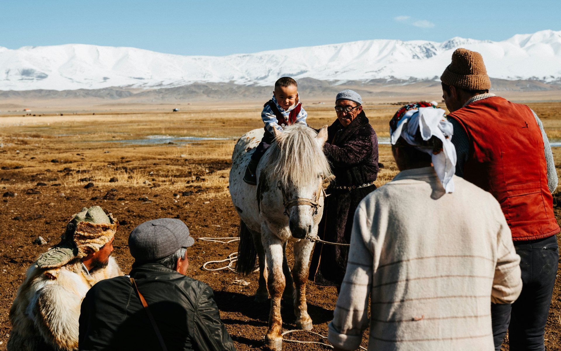 Un enfant sur le dos d'un cheval mongol devant la chaine de montagnes Altai en Mongolie