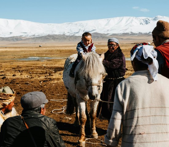 Un enfant sur le dos d'un cheval mongol devant la chaine de montagnes Altai en Mongolie