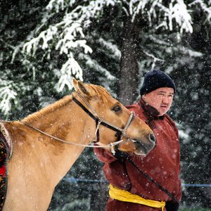 Un homme tient un cheval sous la neige à Ovorhangay en Mongolie