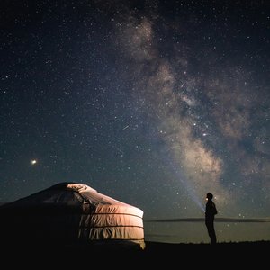 Personne debout à côté d'une tente sous un ciel étoilé en Mongolie